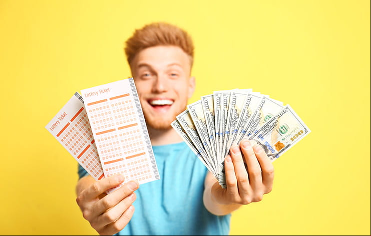 A man holding up lottery tickets and a cash prize